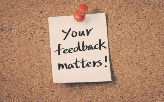 A sign saying 'your feedback matters' is pinned to a corkboard