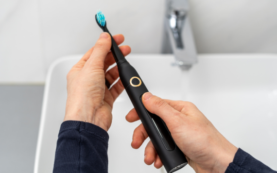 A close-up of an electrical toothbrush held in a hand