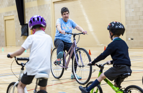 Instructor teaching children how to cycle