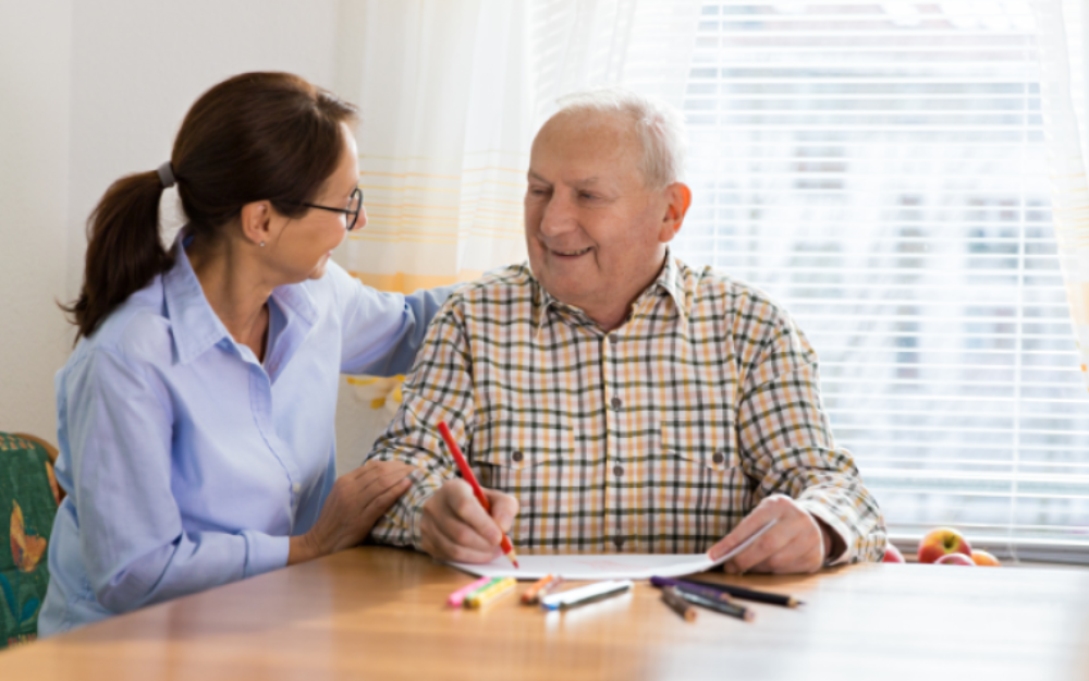 A carer with her arms around an older man, with her arm around him