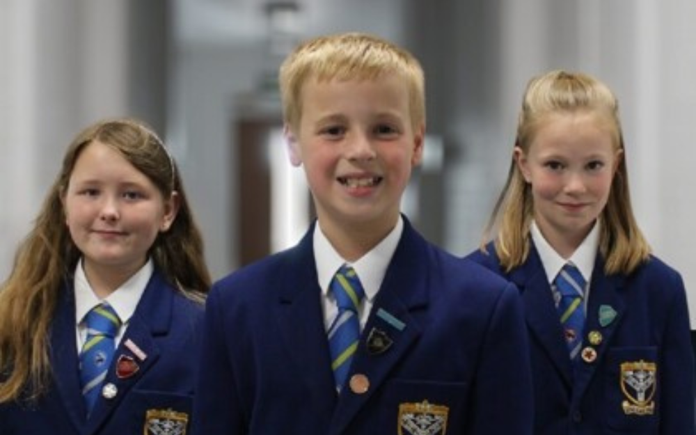 A boy and two girls in the Forest School uniform