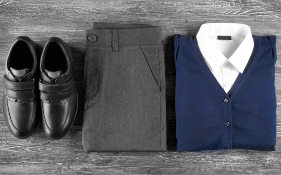 School uniforms including a white shirt inside a blue sweater, grey trousers and black shoes