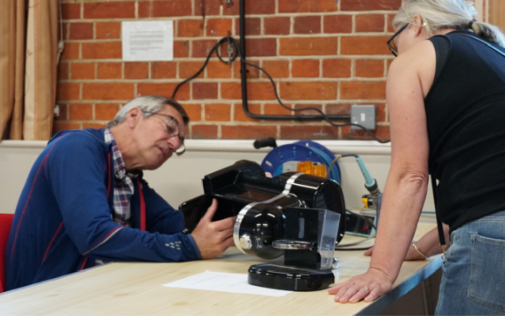 A man makes repairs to a broken item at the Spencers Wood Repair Cafe