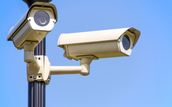 2 white cameras mounted on Black Post Under Clear Blue Sky