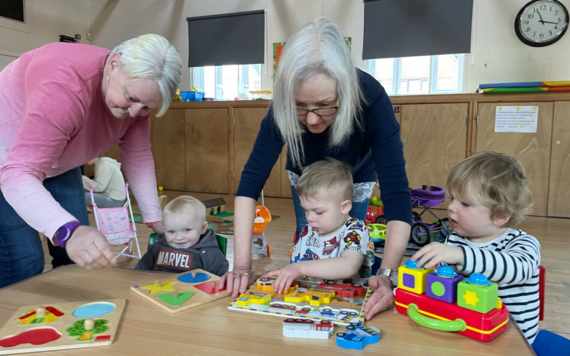 Two Home Start Wokingham team members help play with three young children 