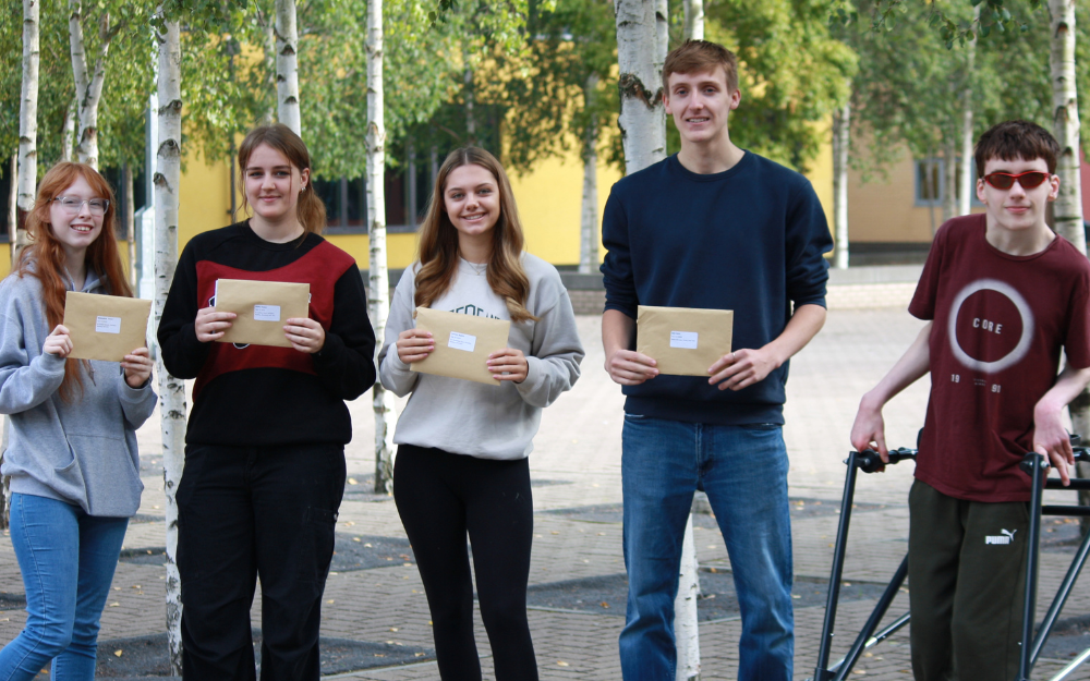 Five students from Waingels College smile with their A Level results envelopes