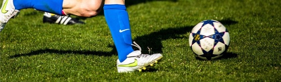 stock image of a pair of feet in boots kicking a football