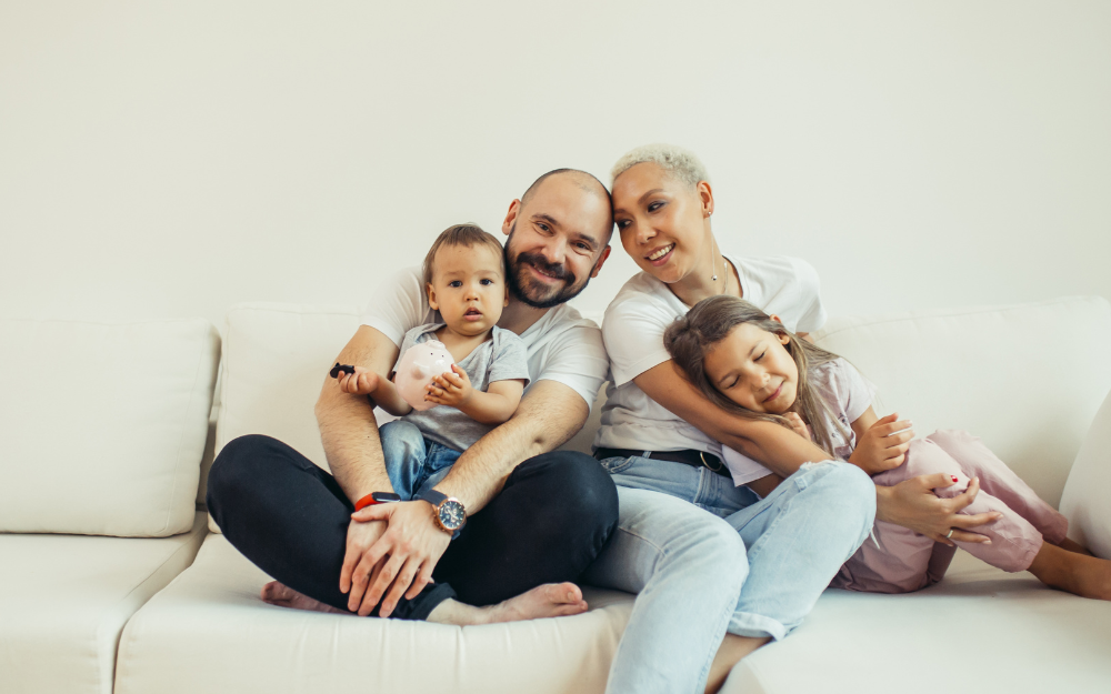 A mother and father cuddled on the sofa with their two children