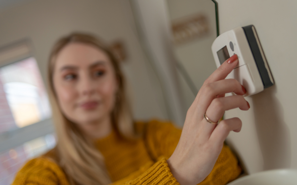 A woman adjusts her thermostat in her home