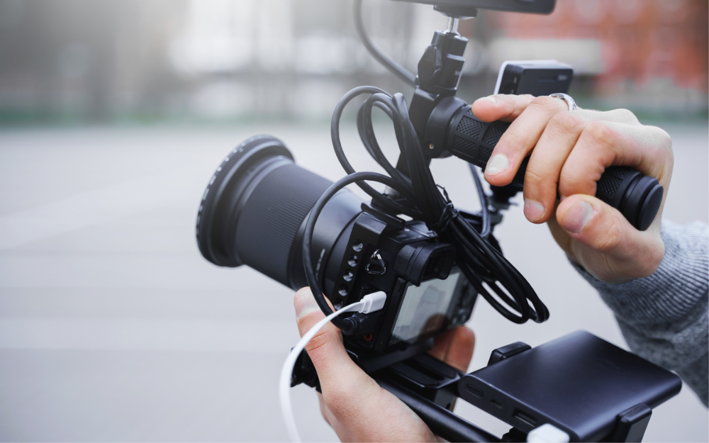 A handheld camera, display and microphone being used for filming