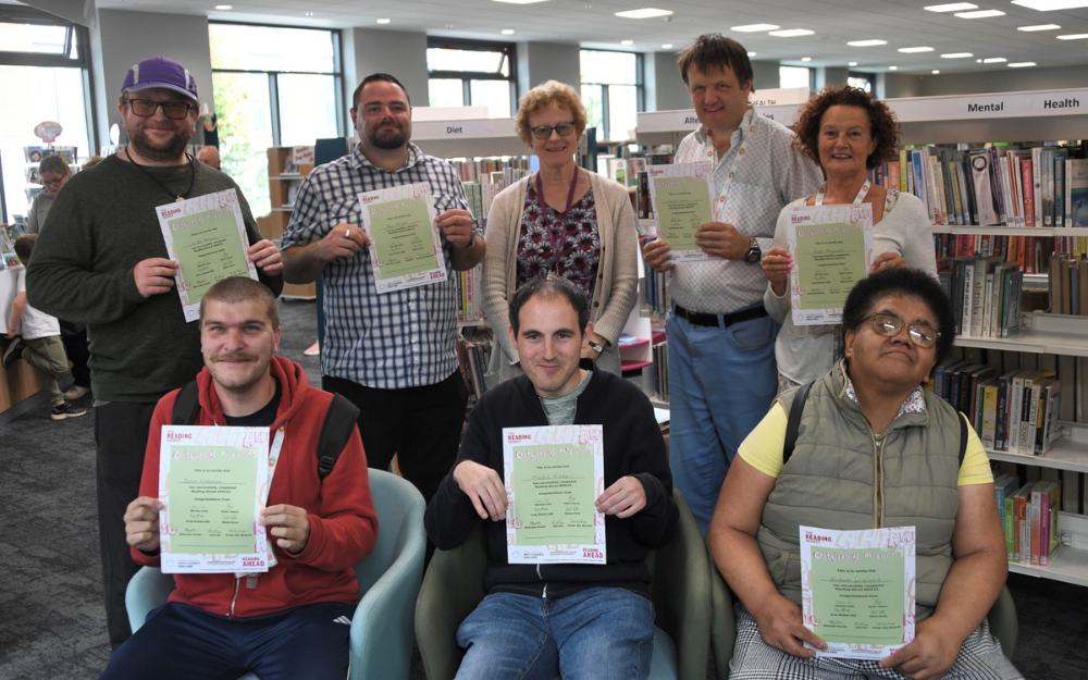 Members of CLASP smile to the camera at Wokingham Library with their certificates for completing the Reading Challenge