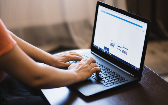 person typing on a lap top on a table