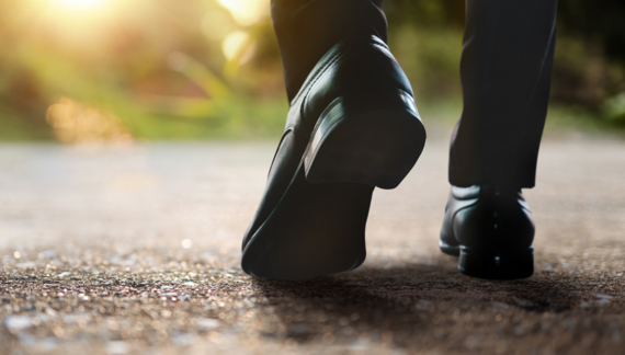 Close up of a pair of feet walking along a pavement