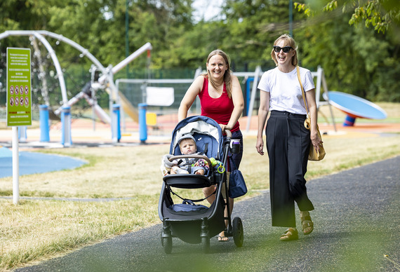 Two ladies walking one pushing a pram with a child
