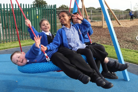 children cram on to a swing seat and smile and pose for the camera while waving and swinging