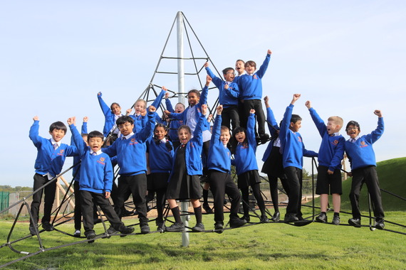 A large group of children climbing up the climbing nets while smiling at the camera and cheering