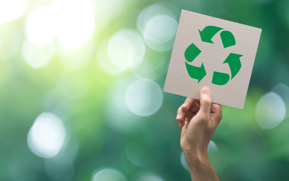 A hand holding up a card with a recycling symbol