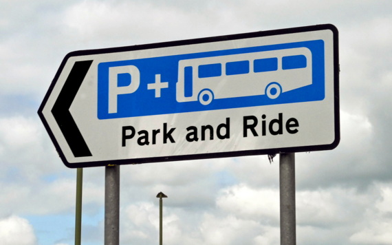 Signpost directing people to a park and ride against a cloudy sky