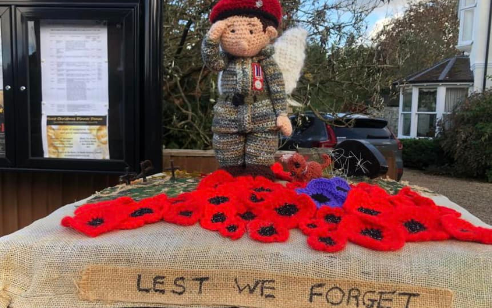 A crochet remembrance post box topper with saluting soldier