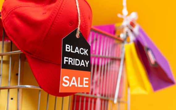 A close-up of a red cap and some shopping bags on a trolley. The tag reads Black Friday sale