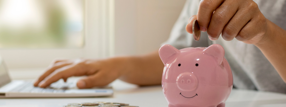 A one pound coin being dropped into a piggy bank