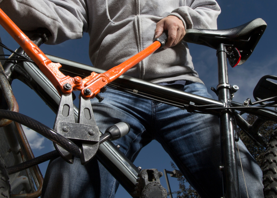 Man using a bolt cutter to cut a lock on a bike