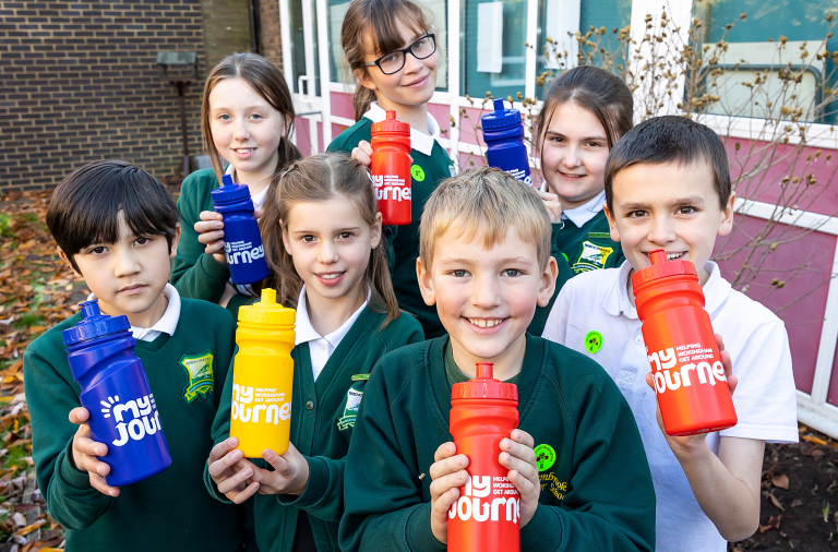 A group of primary school children holding My Journey water bottles