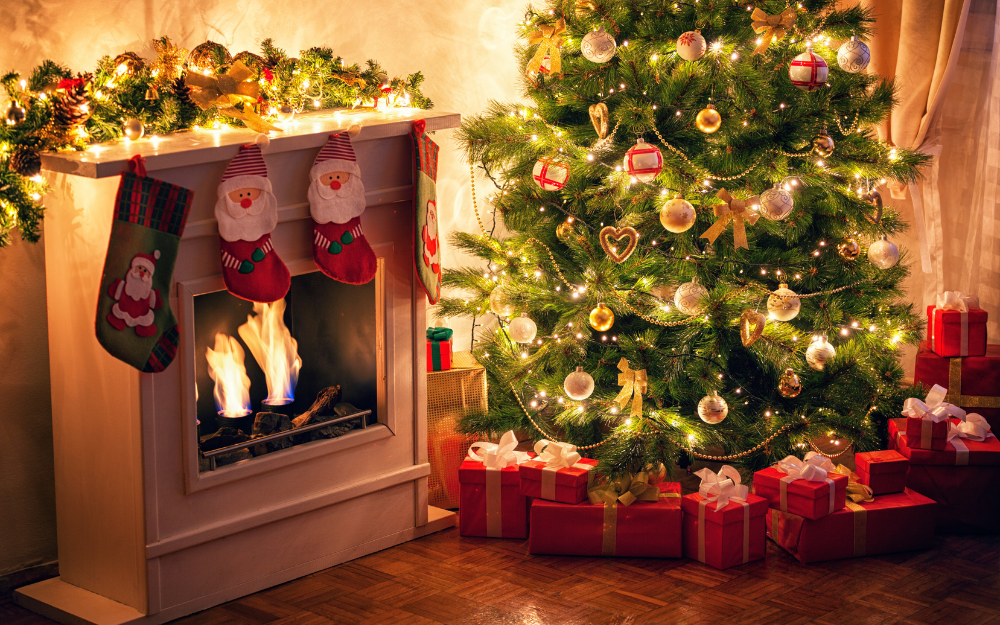 Christmas tree with presents underneath, next to a festive fireplace