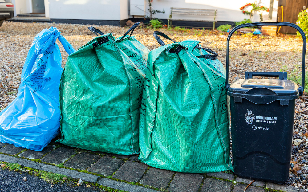 Blue rubbish bag, two green recycling bags and food waste caddy outside a house in Wokingham Borough