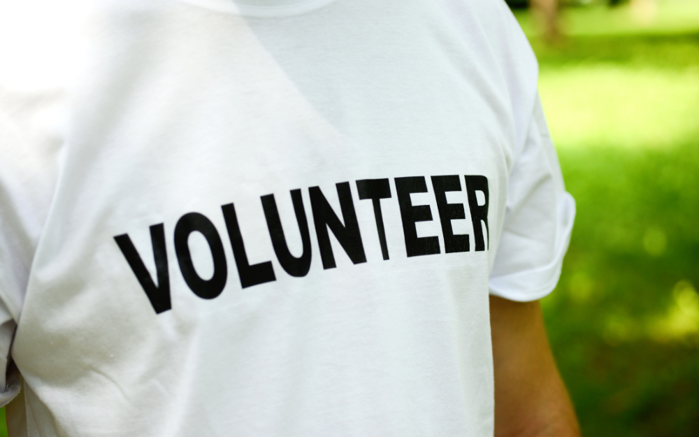 Person wearing a t-shirt which says 'volunteer' on the front