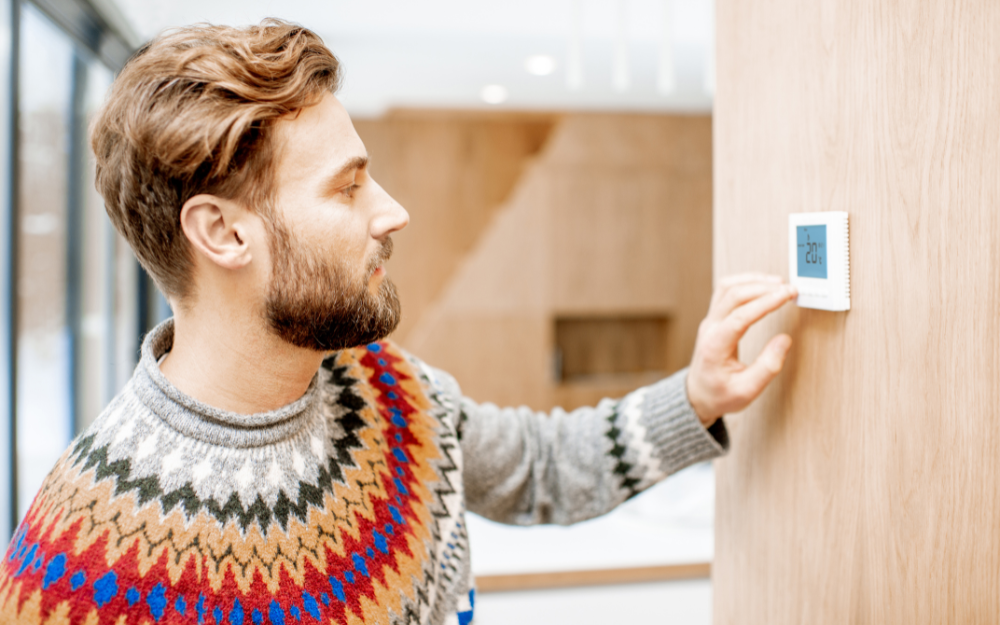 Man adjusting his thermostat in his property