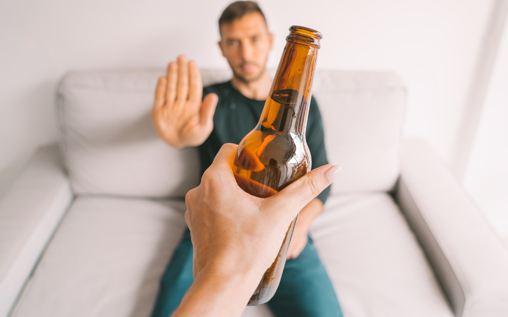 A man holding his hand up to say no when offered a beer