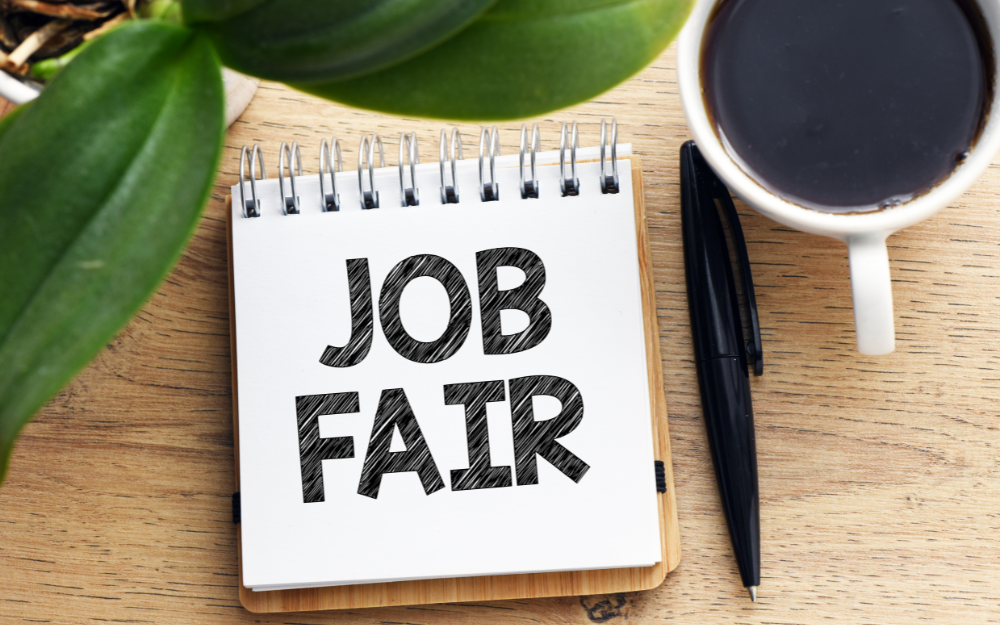 A notepad on a desk which says 'Job Fair'