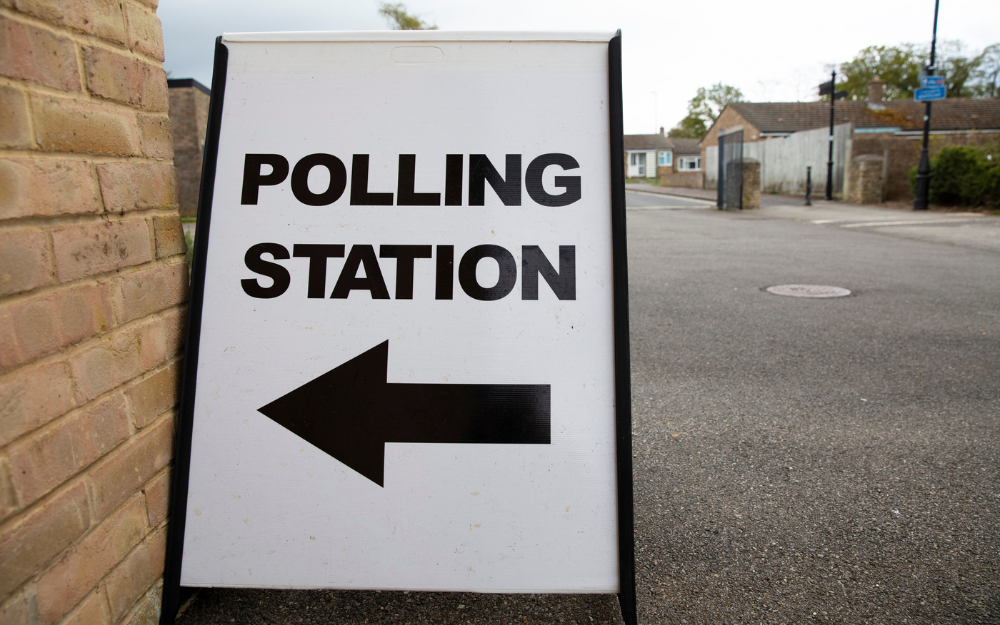 A sign pointing to a polling station in a suburban location