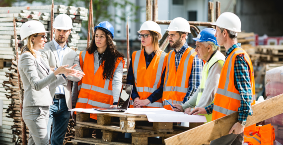 A photo of a mixed group of male and female construction workers on site in hard hats and high viz jackets