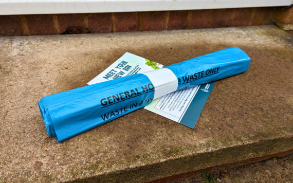 A roll of blue general rubbish bag and a leaflet on the doorstep