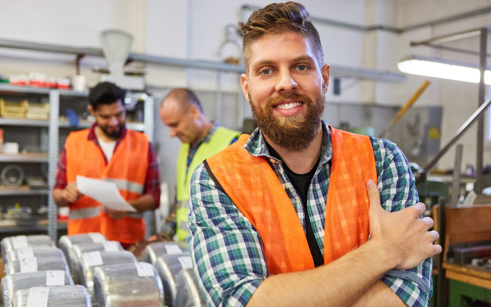 A man wearing a hi-vis jacket smiles to the camera