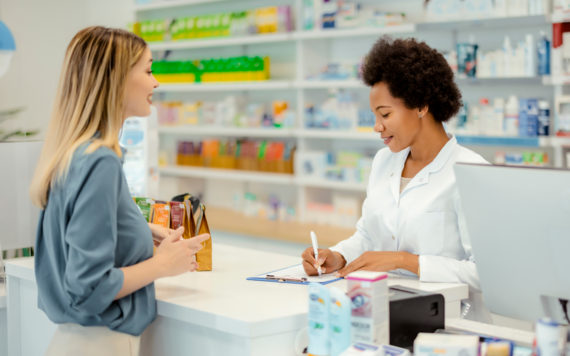 Pharmacist behind a counter helping with a query