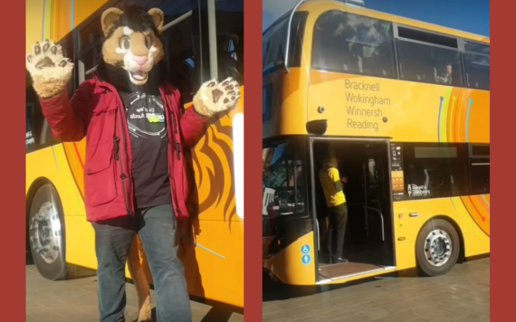 A person wearing a lion costume waving at the camera and the front of the new Lion bus