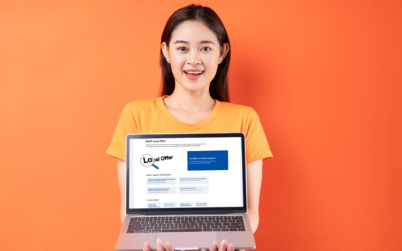 A young woman against an orange background holds up a laptop that shows the local offer webpage
