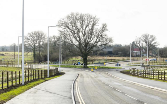 A view of the open area of the south wokingham distributor road leading to a roundabout with a large oak tree in the middle