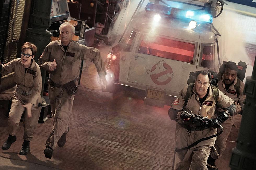 Publicity shot for Ghostbusters showing four characters running into action with their proton guns