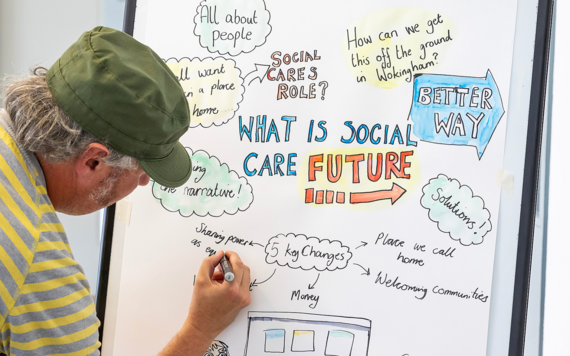 Man writing on a white board at the Social Care Future event 