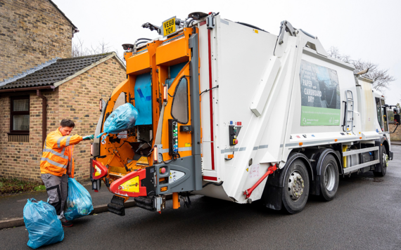 A crew putting bags of rubbish into the back of a waste vehicle