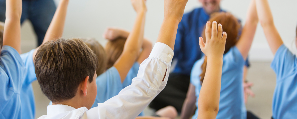 Children with their hands up at primary school