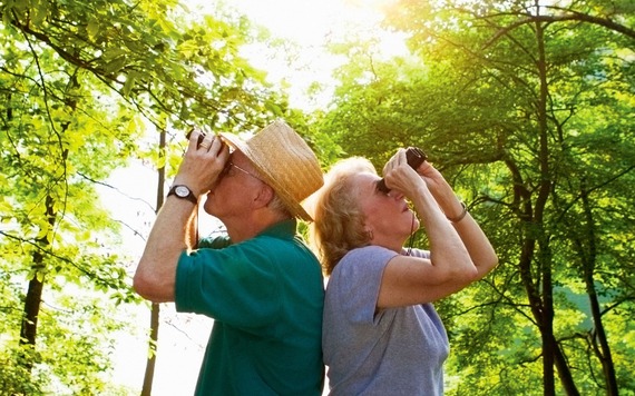 A close-up of a man and a woman watching bird with a binocular