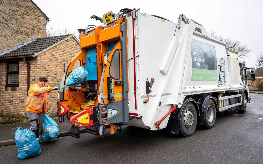Blue rubbish bags being placed into a bin truck