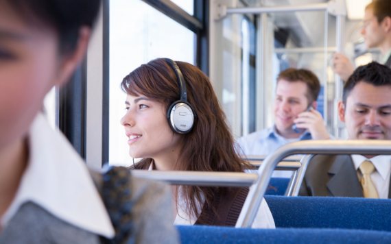 Five people in smart attire sitting and standing on a bus