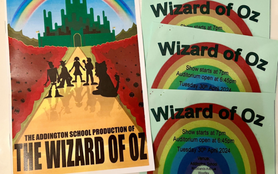A colourful printed programme with the main characters from The Wizard of Oz, next to three tickets with rainbows on them
