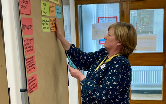 Woman putting post its onto a board under the heading root causes